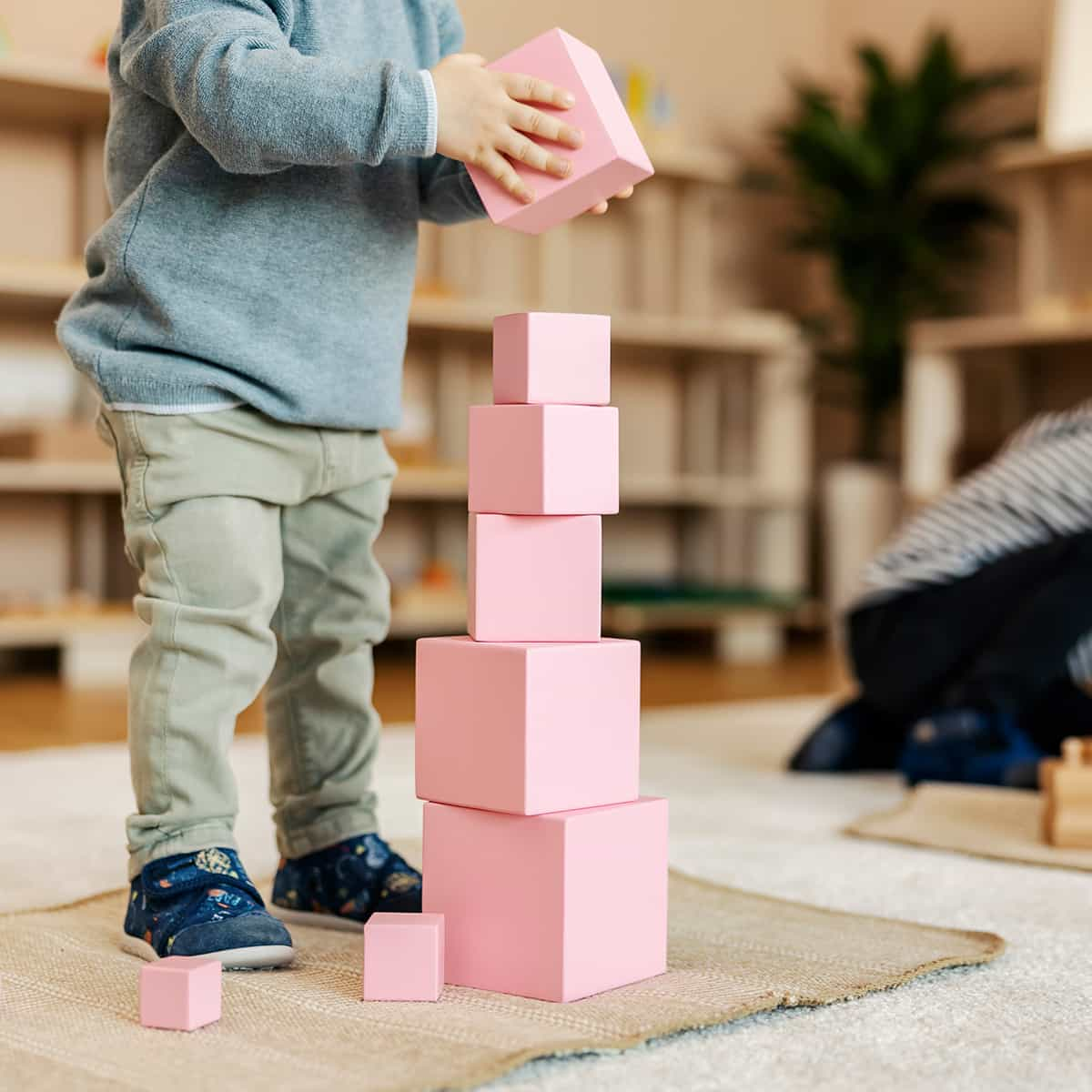 Ein Kind baut einen Turm aus rosa Bauklötzen