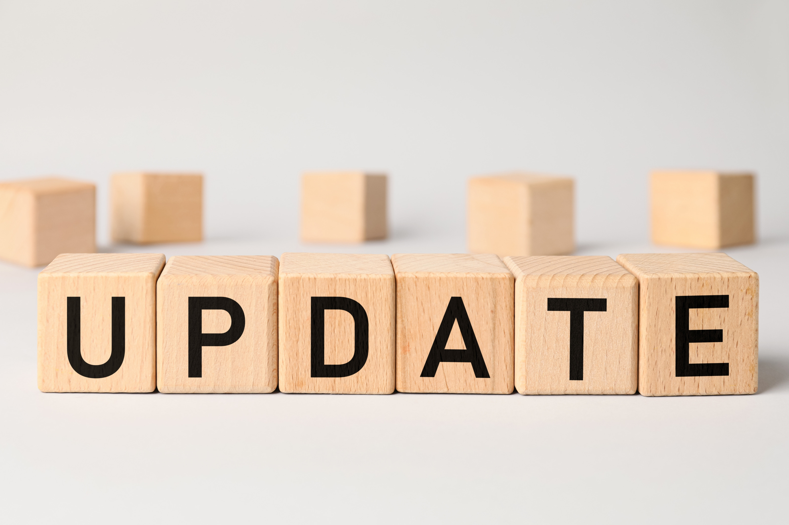 Nebeneinander gereihte Holzwürfel auf einer hellen Oberfläche, die gemeinsam Schriftzug Update ergeben