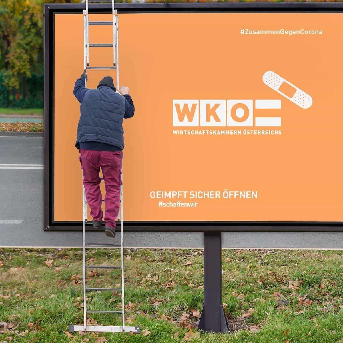 Mann auf Leiter vor einem WKO Plakat