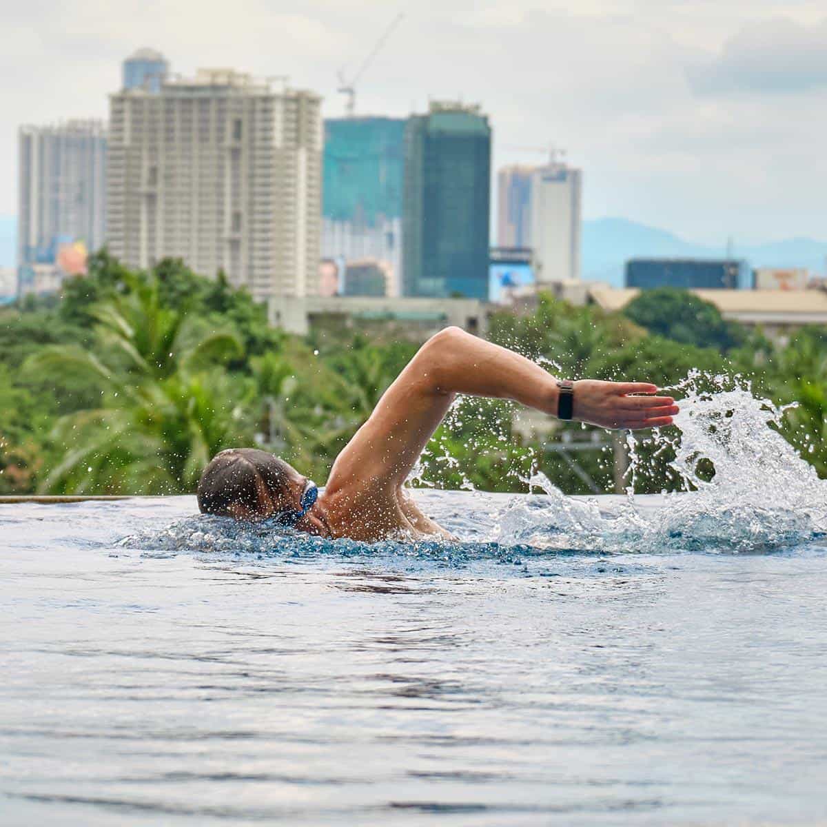 Mann schwimmt vor der Skyline von Manila