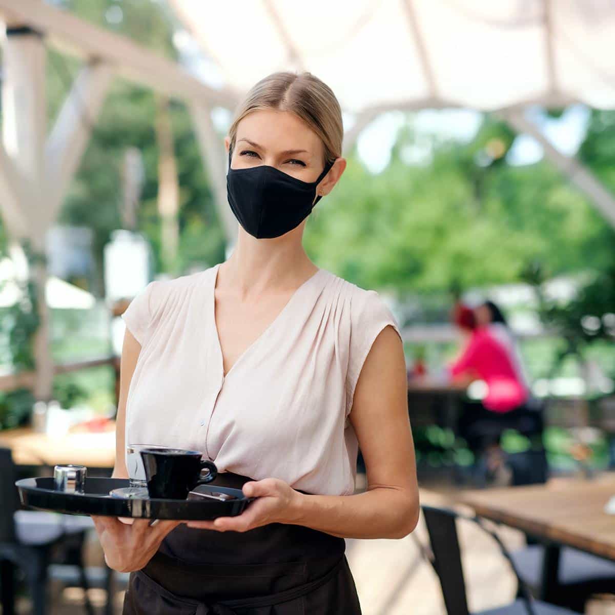 Kellnerin mit Maske im Gastgarten