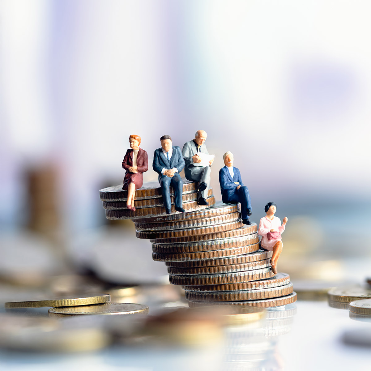 Miniaturfiguren älterer Menschen sitzen auf unterschiedlich hohen Münzstapeln.