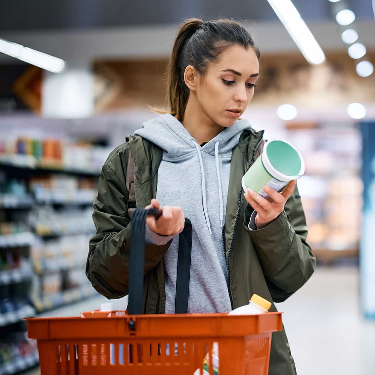 Junge Frau im Supermarkt betrachtet Lebensmittel