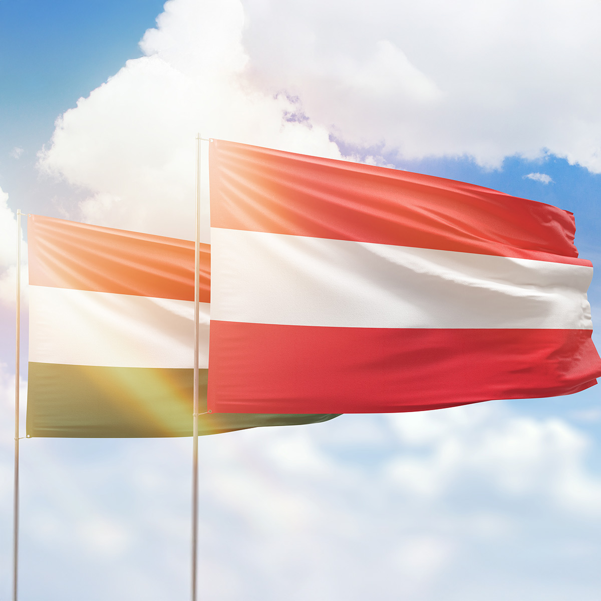 Österreich- und Ungarnflagge bei Sonnenschein und vor blauem Himmel
